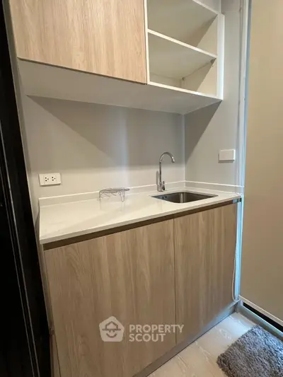 Modern compact kitchen with sleek wooden cabinets and stainless steel sink