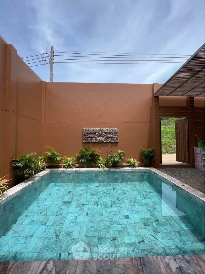 Luxurious private pool with elegant stone tiles and lush greenery in a serene outdoor setting.