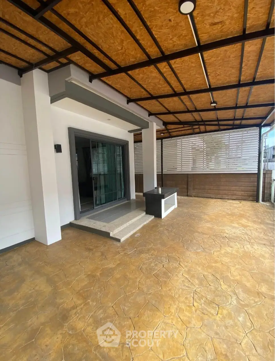 Spacious covered patio with modern design and sliding glass doors.