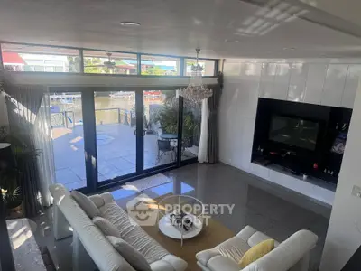 Luxurious living room with waterfront view, elegant chandelier, and modern decor in a stylish home.