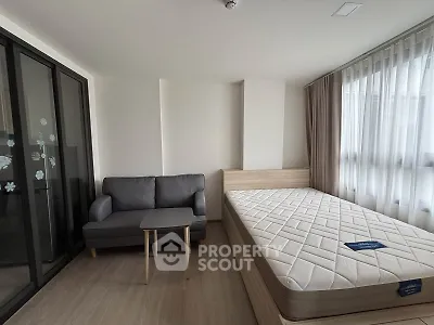 Modern bedroom with cozy sofa and large window, perfect for urban living.