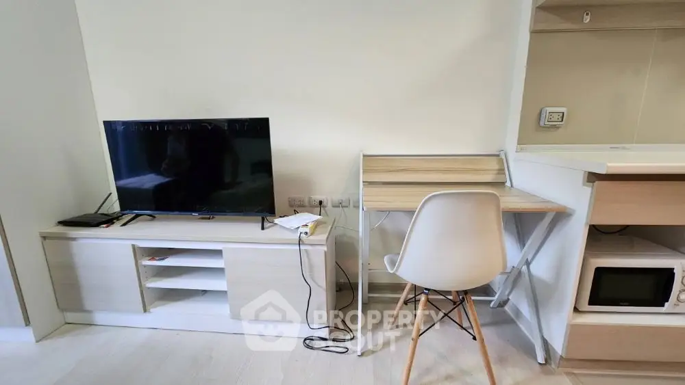 Modern apartment interior with TV, desk, and microwave in a compact living space.