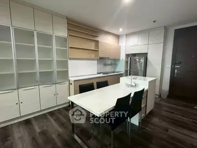 Modern kitchen with sleek cabinetry and dining area in contemporary apartment.