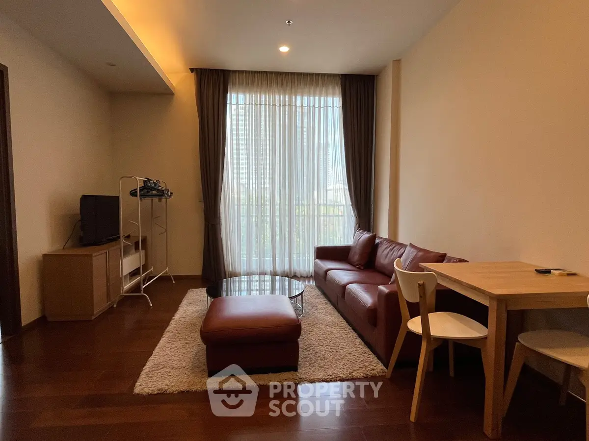 Modern living room with leather sofa, wooden flooring, and large window with city view.