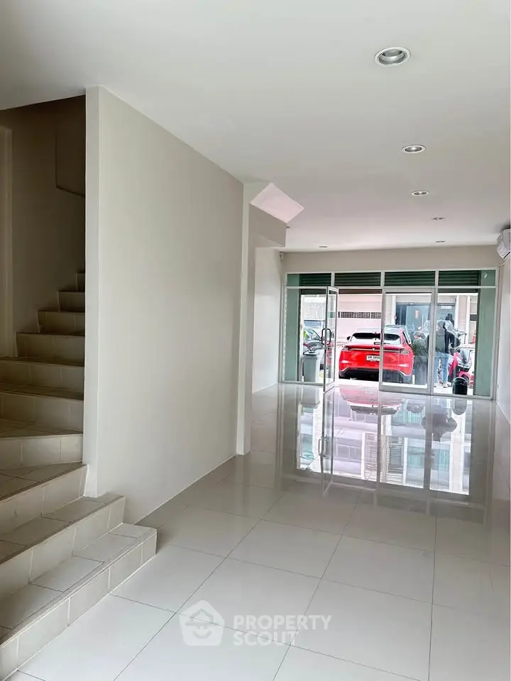 Spacious modern living room with glossy tiled floors and large glass doors leading to a garage.