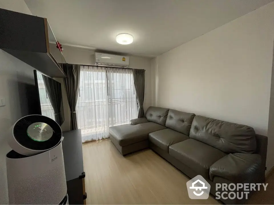 Modern living room with sleek gray sofa and air purifier, featuring natural light from large window.