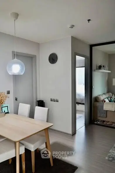 Modern dining area with sleek furniture and open view into cozy living room and bedroom.