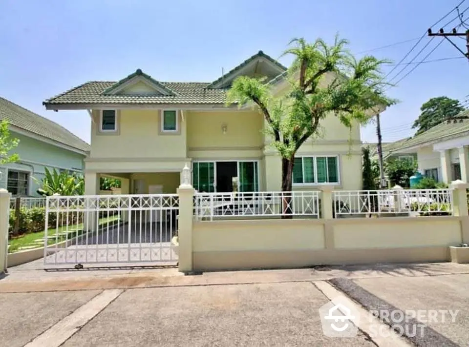 Charming two-story house with lush garden and gated entrance in a serene neighborhood.