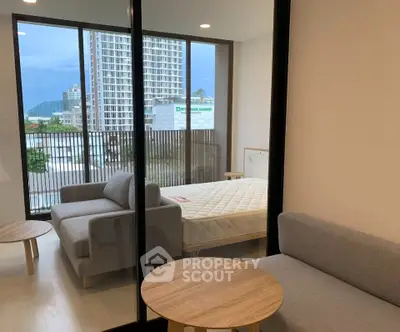Modern studio apartment with large windows and cozy furniture, offering a bright and inviting living space.