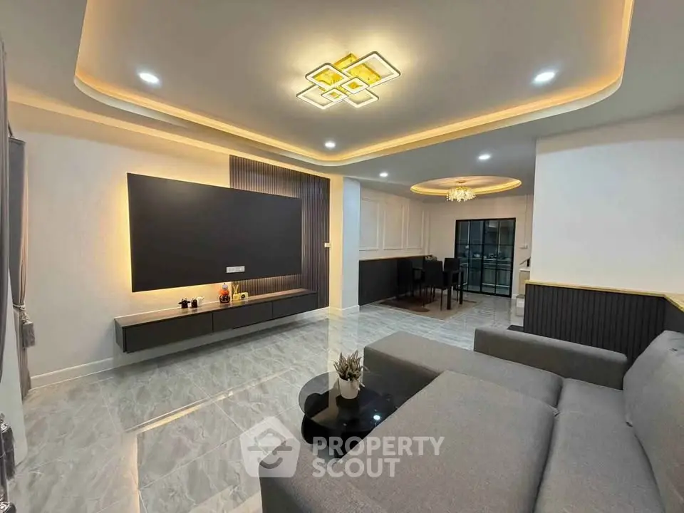 Modern living room with sleek design, featuring a large gray sofa, stylish lighting, and elegant flooring.