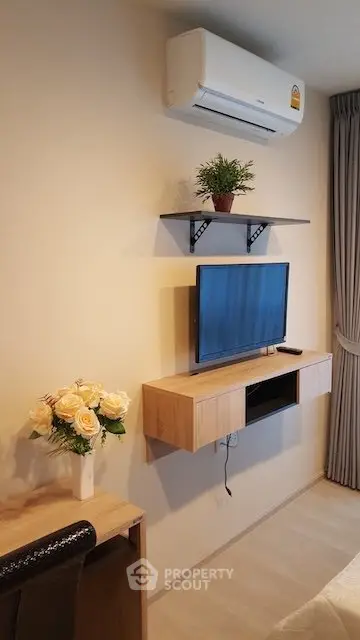 Modern living room with wall-mounted TV and air conditioning, featuring elegant decor and natural light.
