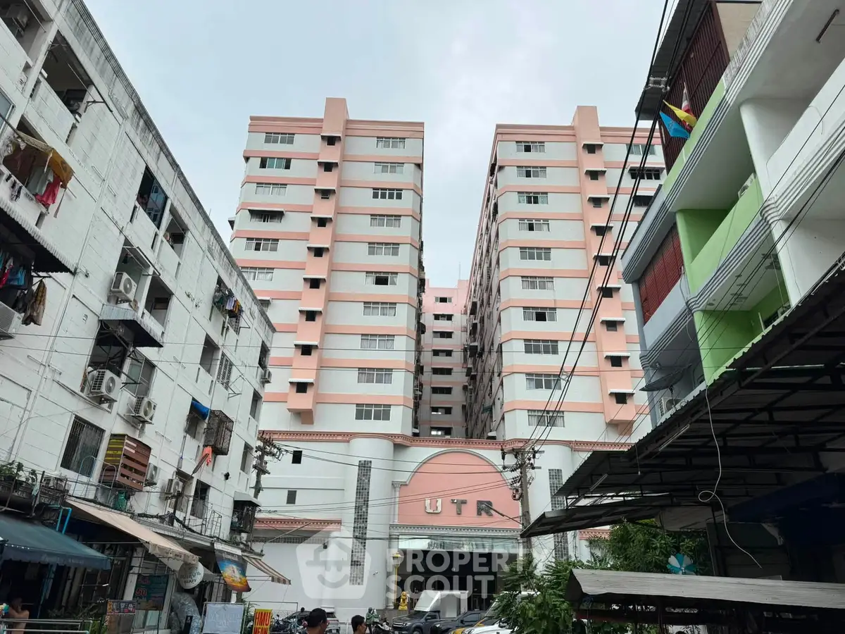 High-rise residential building with pink facade and multiple balconies in urban setting.