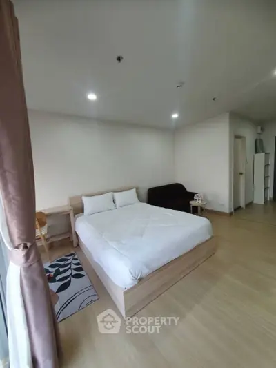 Spacious bedroom with modern decor and natural light, featuring a cozy bed and stylish furnishings.