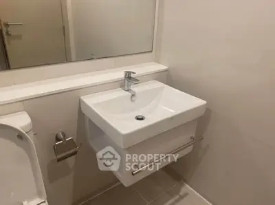 Sleek modern bathroom with wall-mounted sink, large mirror, and pristine white fixtures, perfect for contemporary living.