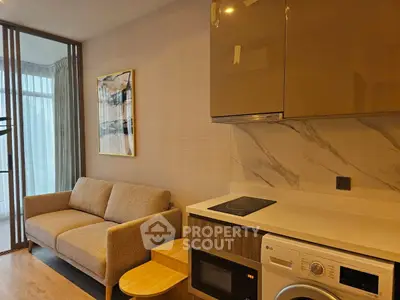 Modern apartment interior with cozy living room and compact kitchen featuring washing machine and microwave.
