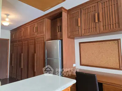 Spacious kitchen with wooden cabinets and modern fridge, perfect for culinary enthusiasts.