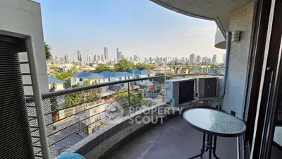 Stunning cityscape view from a modern balcony with sleek railing and outdoor seating.