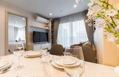 Modern living room with elegant dining setup and large window view.