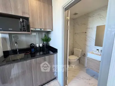 Modern compact kitchen with adjacent stylish bathroom in a sleek apartment unit.