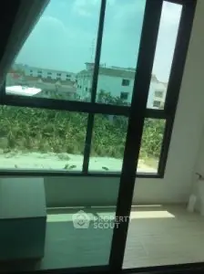 Bright room with large window offering a view of greenery and distant buildings.