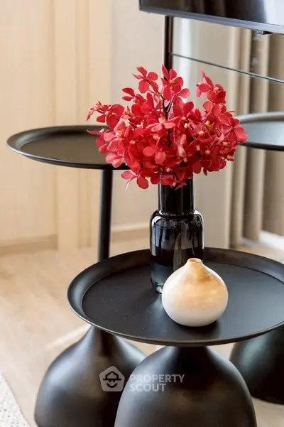 Stylish modern interior decor with black side tables and vibrant red flowers.