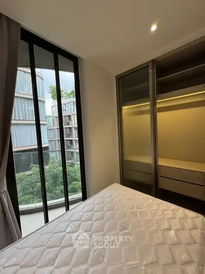 Modern bedroom with large window and built-in closet in urban apartment