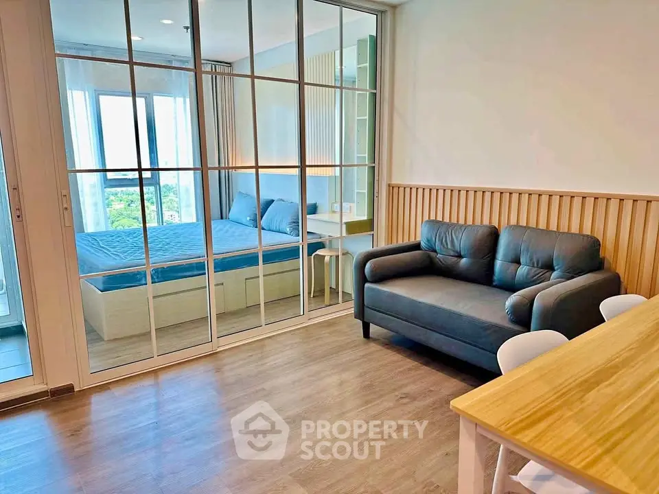 Modern apartment with glass partitioned bedroom and cozy living area, featuring stylish decor and natural light.