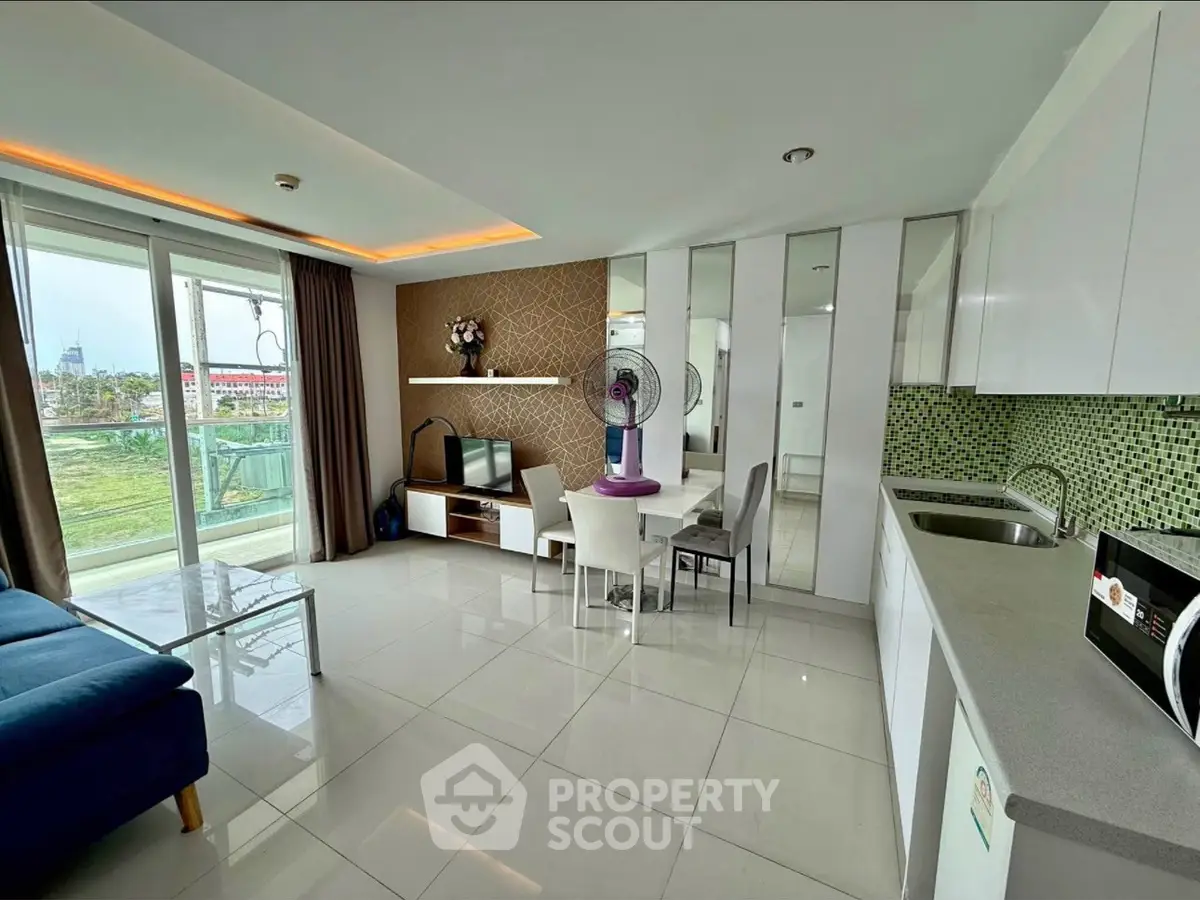 Modern open-layout living room with kitchen, featuring sleek design and large windows for natural light.