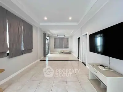 Spacious modern living room with sleek tile flooring and large TV setup.