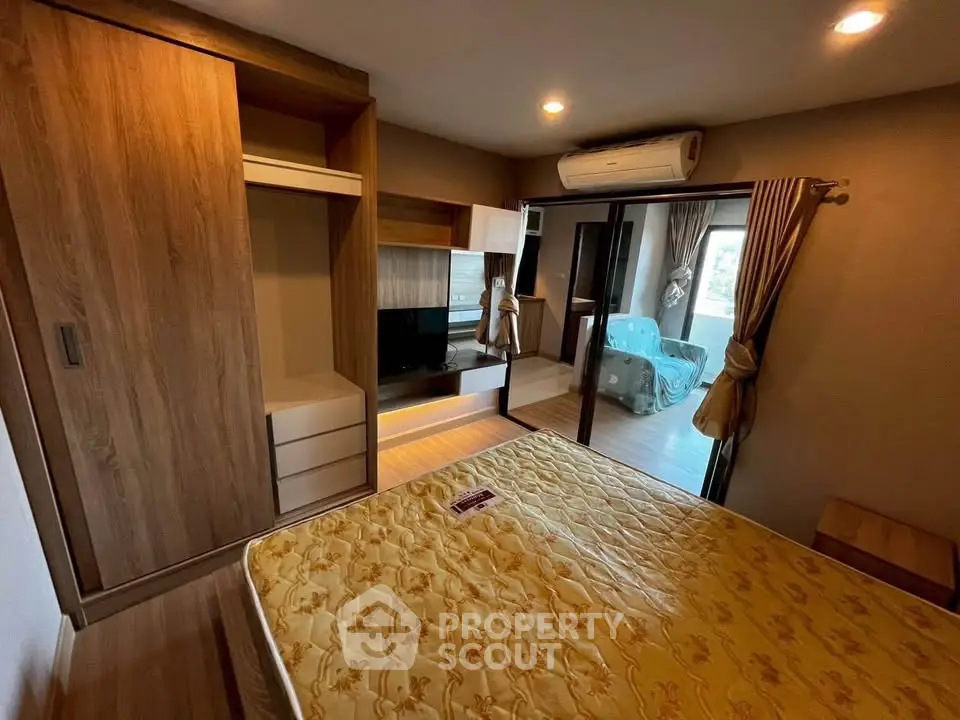 Modern bedroom with wooden furniture and sliding glass doors leading to a cozy living area.