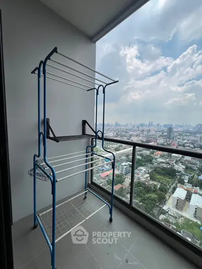 High-rise balcony with cityscape view and drying rack, perfect for urban living.