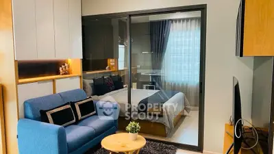 Modern apartment with cozy living room and stylish bedroom separated by glass wall.