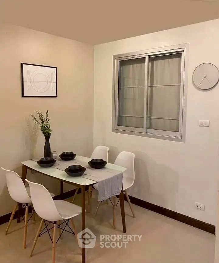 Modern dining area with sleek table and chairs, minimalist decor, and wall art in a cozy apartment.