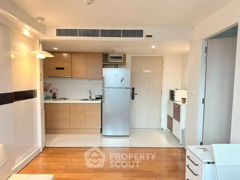 Modern kitchen with sleek cabinetry and stainless steel fridge in a cozy apartment setting.