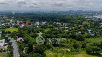 Expansive aerial view of lush green landscape with distant mountains, ideal for real estate development.