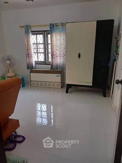 Spacious bedroom with modern wardrobe and large window for natural light.