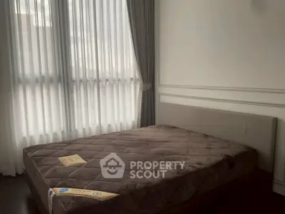 Cozy bedroom with large window and elegant curtains, featuring a plush bed in a modern apartment.