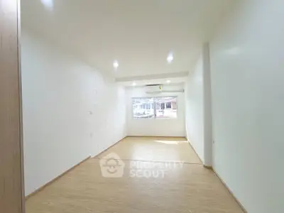 Spacious unfurnished room with large window and wooden flooring, perfect for customization.