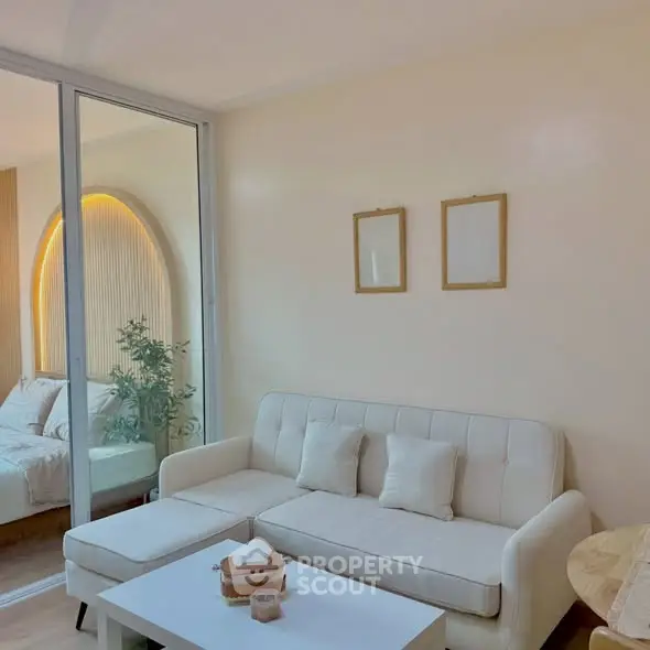 Modern living room with white sofa and glass partition to bedroom.