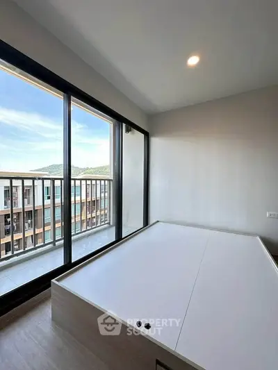 Modern bedroom with large windows and balcony offering scenic views, perfect for urban living.