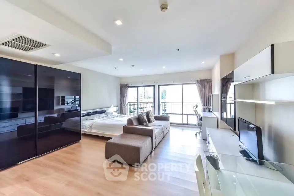 Spacious modern studio apartment with open layout and large windows for natural light.