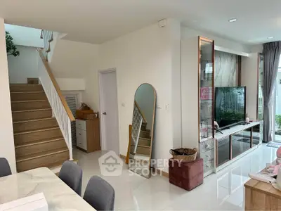 Modern living room with sleek TV unit and elegant staircase in a stylish home.