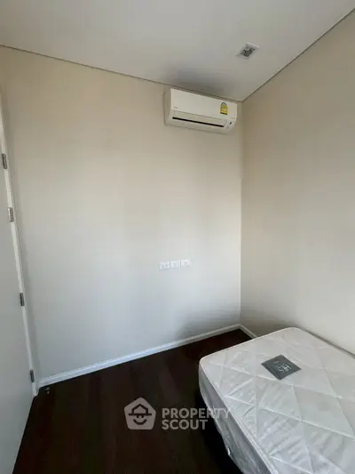 Minimalist bedroom with air conditioning and hardwood floors, perfect for a cozy living space.