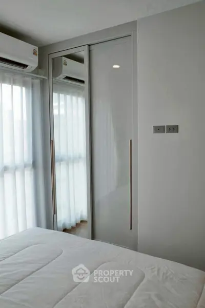 Modern bedroom with sleek wardrobe and natural light through large windows.