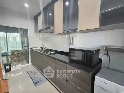 Modern kitchen with sleek cabinetry and appliances, open layout leading to dining area.