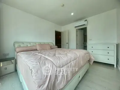 Spacious bedroom with modern decor and ample natural light, featuring a comfortable bed and sleek furniture.