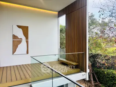 Modern balcony with glass railing and wooden accents overlooking lush greenery.