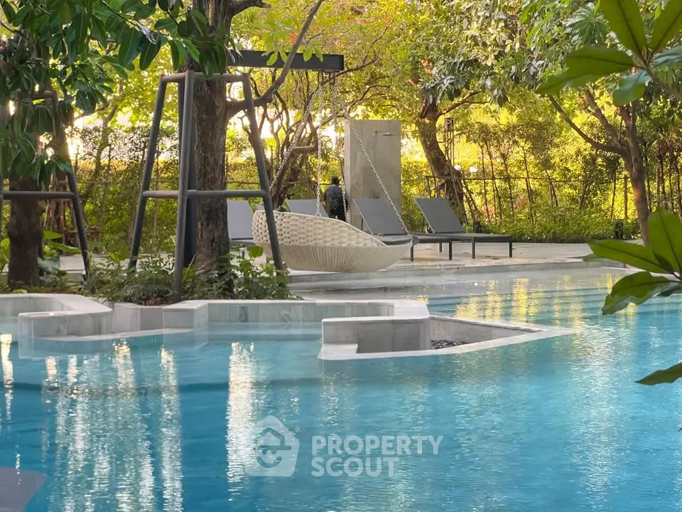 Luxurious outdoor pool area with modern lounge chairs and lush greenery, perfect for relaxation and leisure.