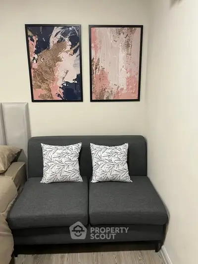 Cozy corner with modern gray sofa and abstract art in stylish bedroom.