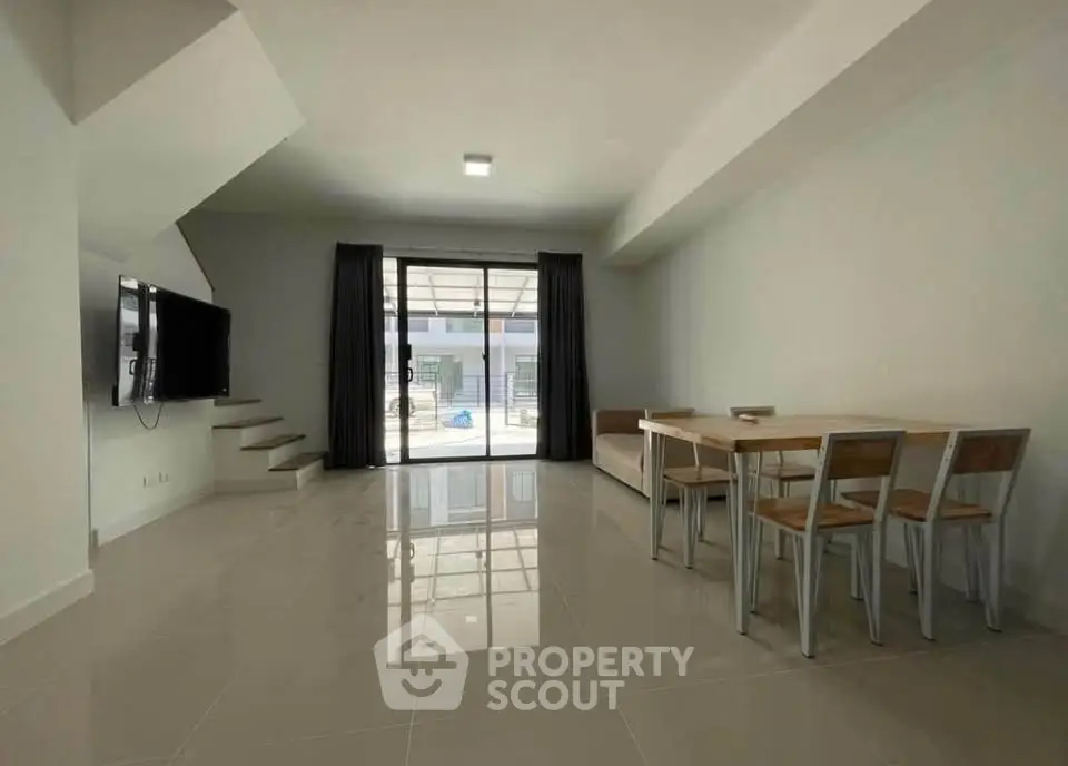 Modern living room with sleek design and open layout, featuring a wall-mounted TV and dining area.